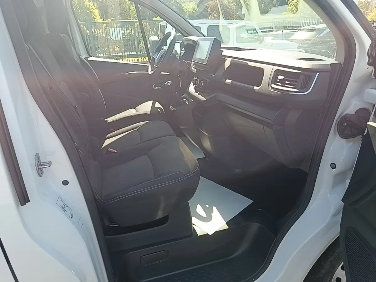 Vue intérieure côté conducteur du Renault Trafic Fourgon blanc 2023, montrant les sièges et le tableau de bord.
