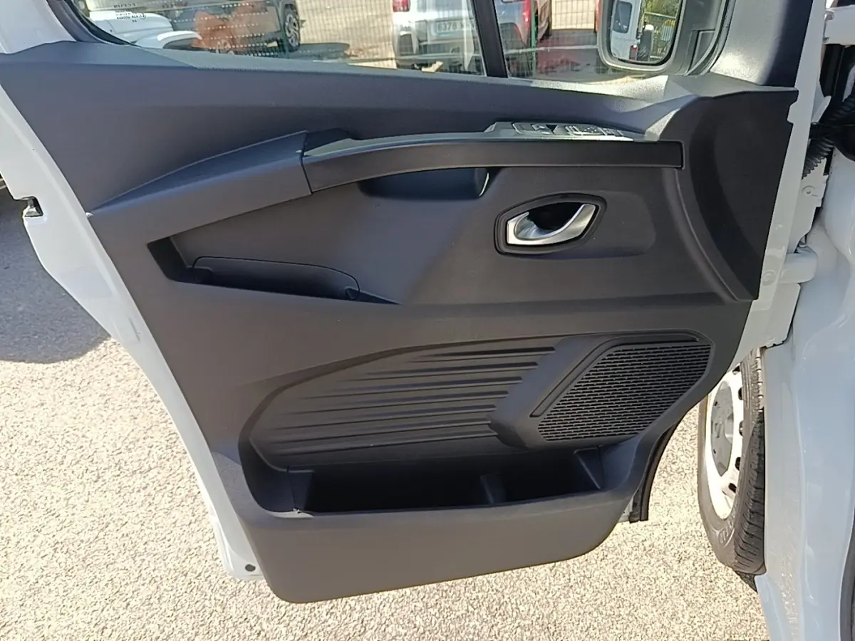 Vue rapprochée de la porte avant droite blanche du Renault Trafic Fourgon 2023 avec panneau intérieur noir et poignée argentée.