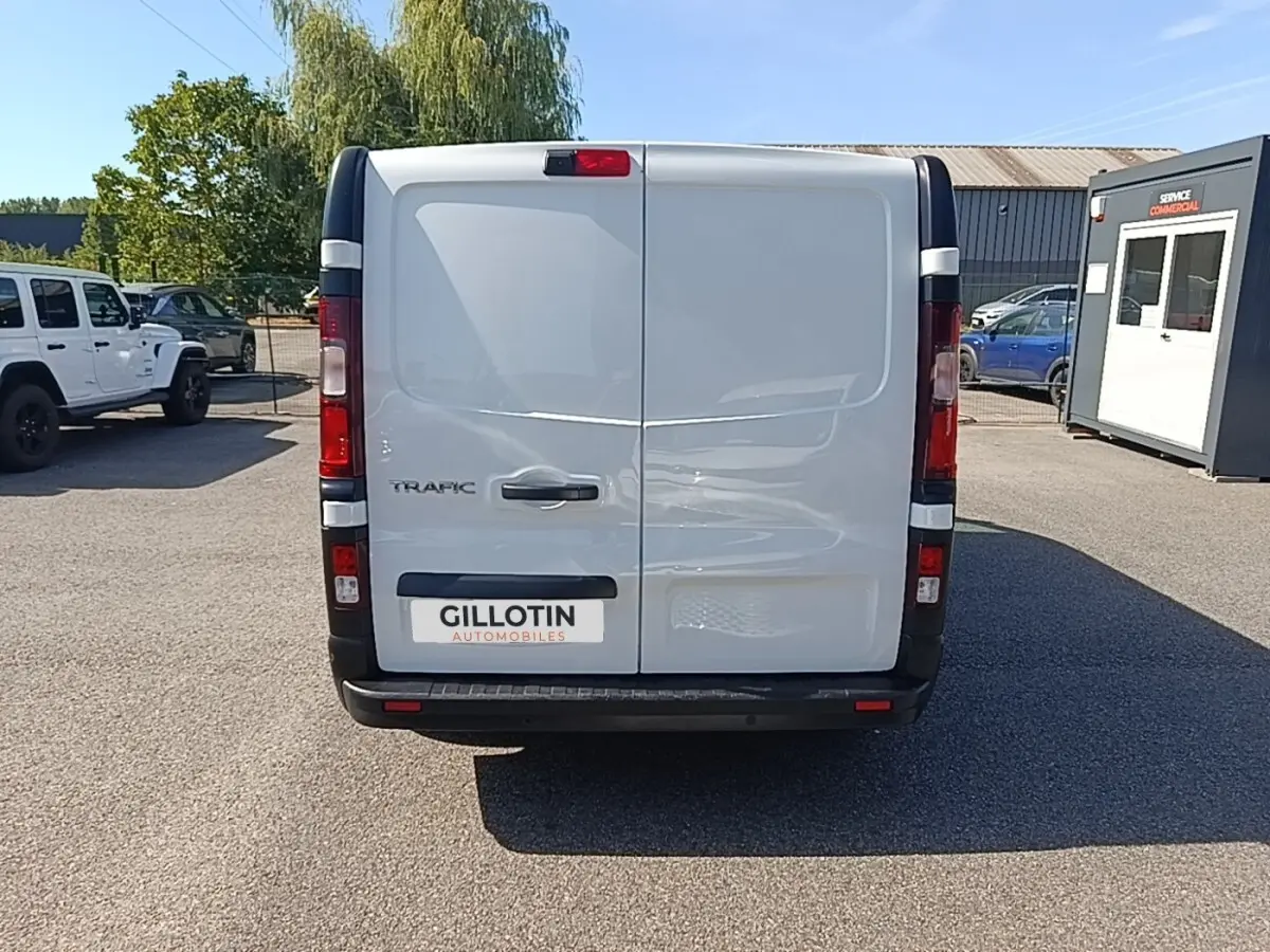 Vue arrière d'un Renault Trafic Fourgon blanc 2023 avec portes battantes et feux arrière verticaux.