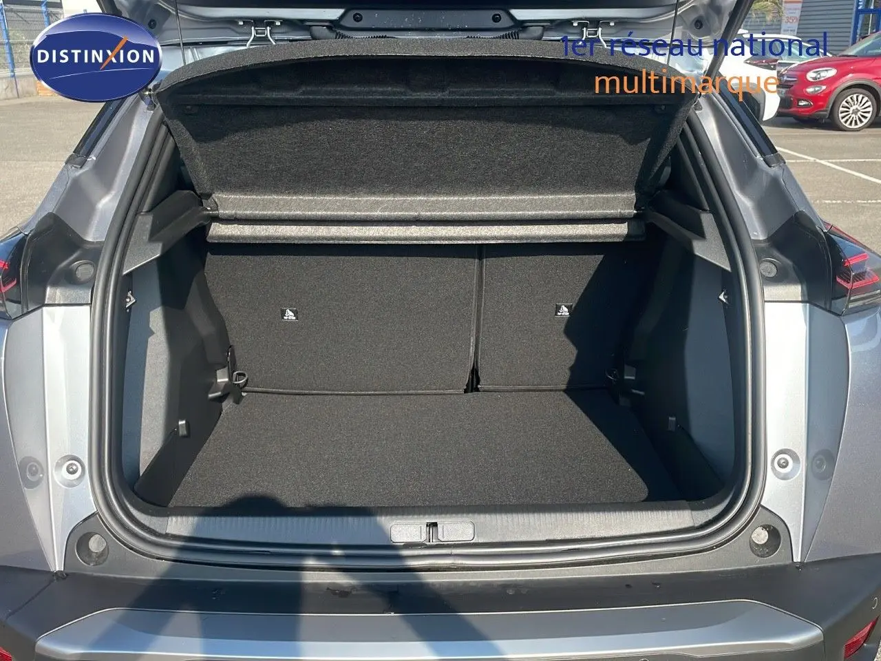 Coffre ouvert vu de l'arrière d'un Peugeot 2008 gris Artense métal, montrant l'espace de chargement vide.