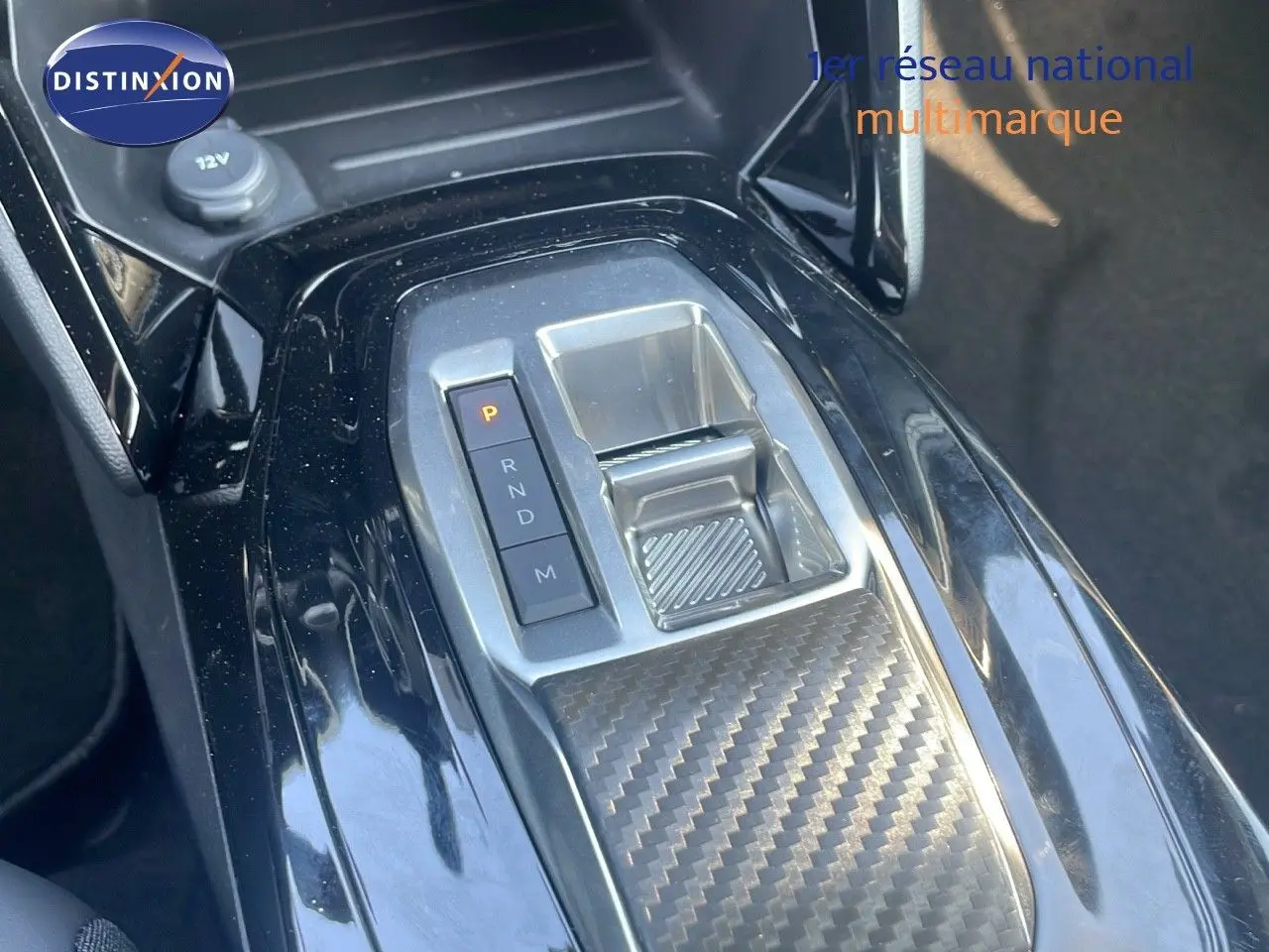 Gros plan sur la console centrale de la Peugeot 2008 Hybrid 136ch Allure 2025, avec levier de vitesses automatique et finition carbone.