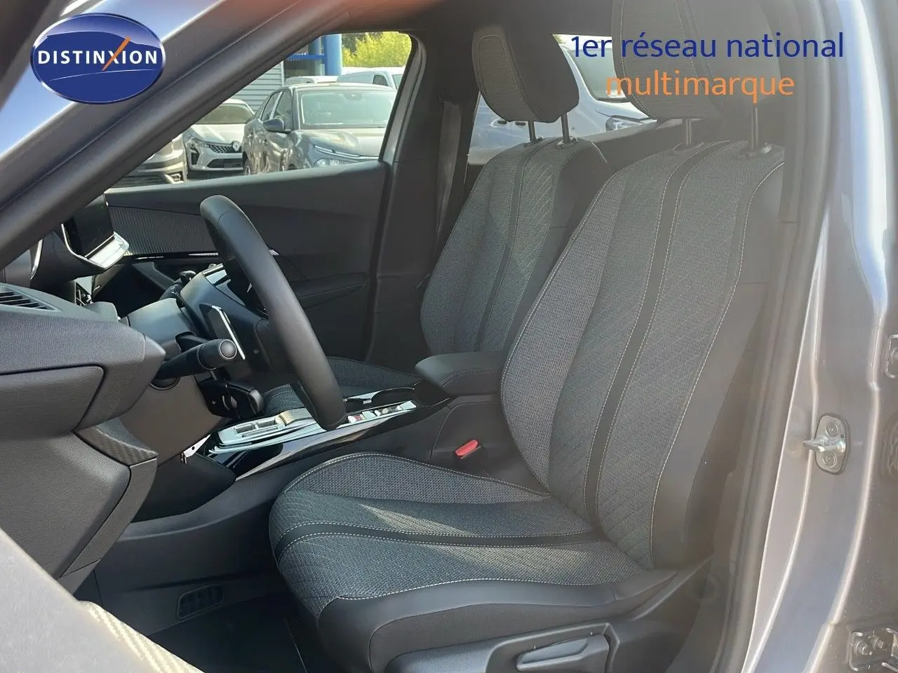 Vue intérieure côté conducteur du Peugeot 2008 gris Artense, mettant en valeur les sièges tissu et la console centrale moderne.