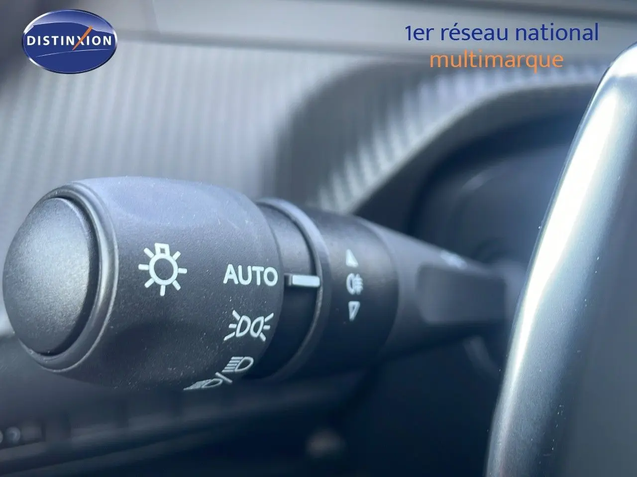 Gros plan sur la commande des phares du Peugeot 2008 gris Artense, à l'intérieur côté conducteur.
