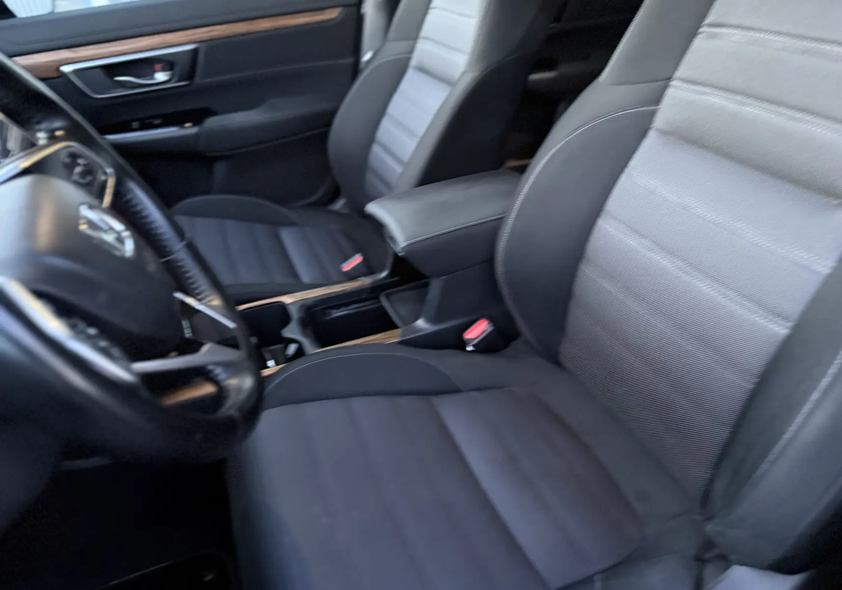 Vue intérieure du Honda CR-V Hybrid 2019 montrant les sièges avant en tissu gris et noir avec accoudoir central.