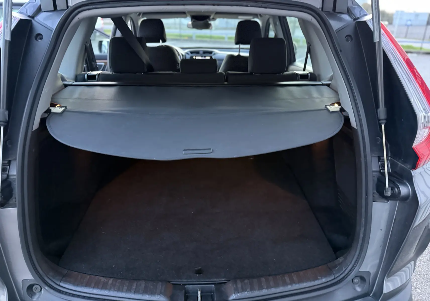 Coffre ouvert d’un Honda CR-V Hybrid 184 Elegance gris, vue arrière montrant la plage arrière et l’habitacle.