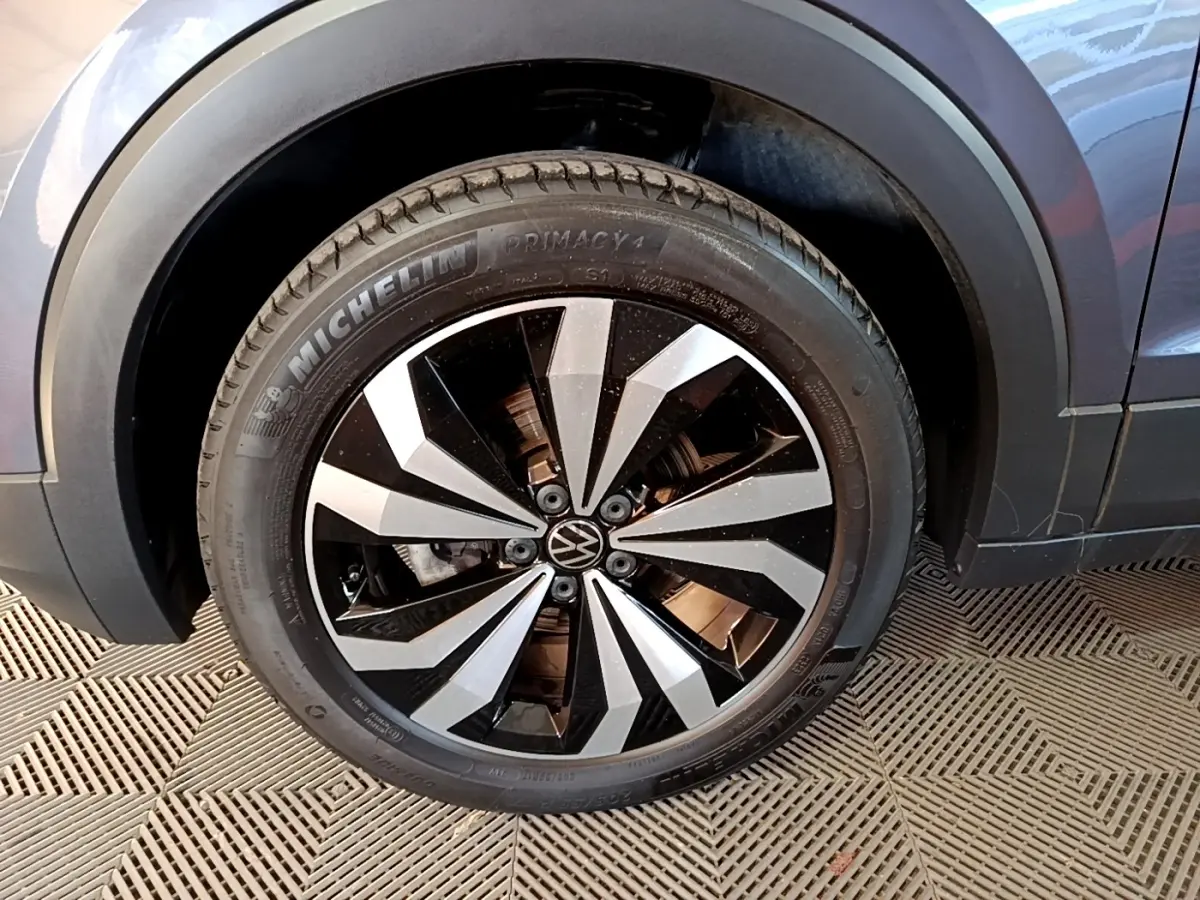 Gros plan sur la roue avant droite du Volkswagen T-Cross gris foncé, avec jante alliage bicolore et pneu Michelin.