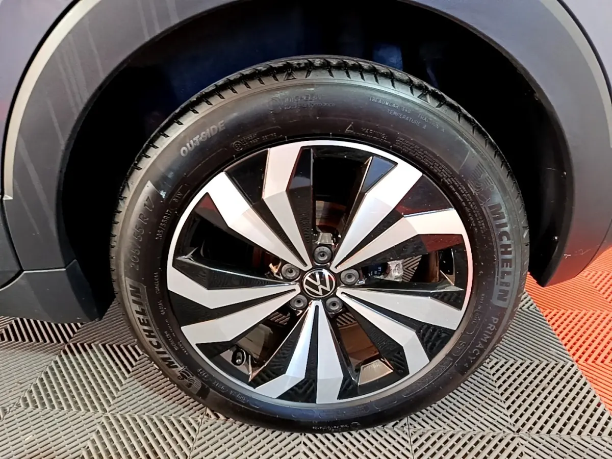 Gros plan sur la roue avant droite du Volkswagen T-Cross gris foncé avec jante alliage bicolore distinctive.