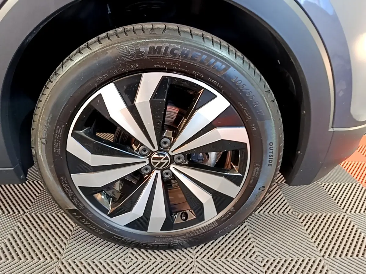 Gros plan sur la roue avant droite du Volkswagen T-Cross gris foncé, avec jante alliage bicolore et pneu Michelin.