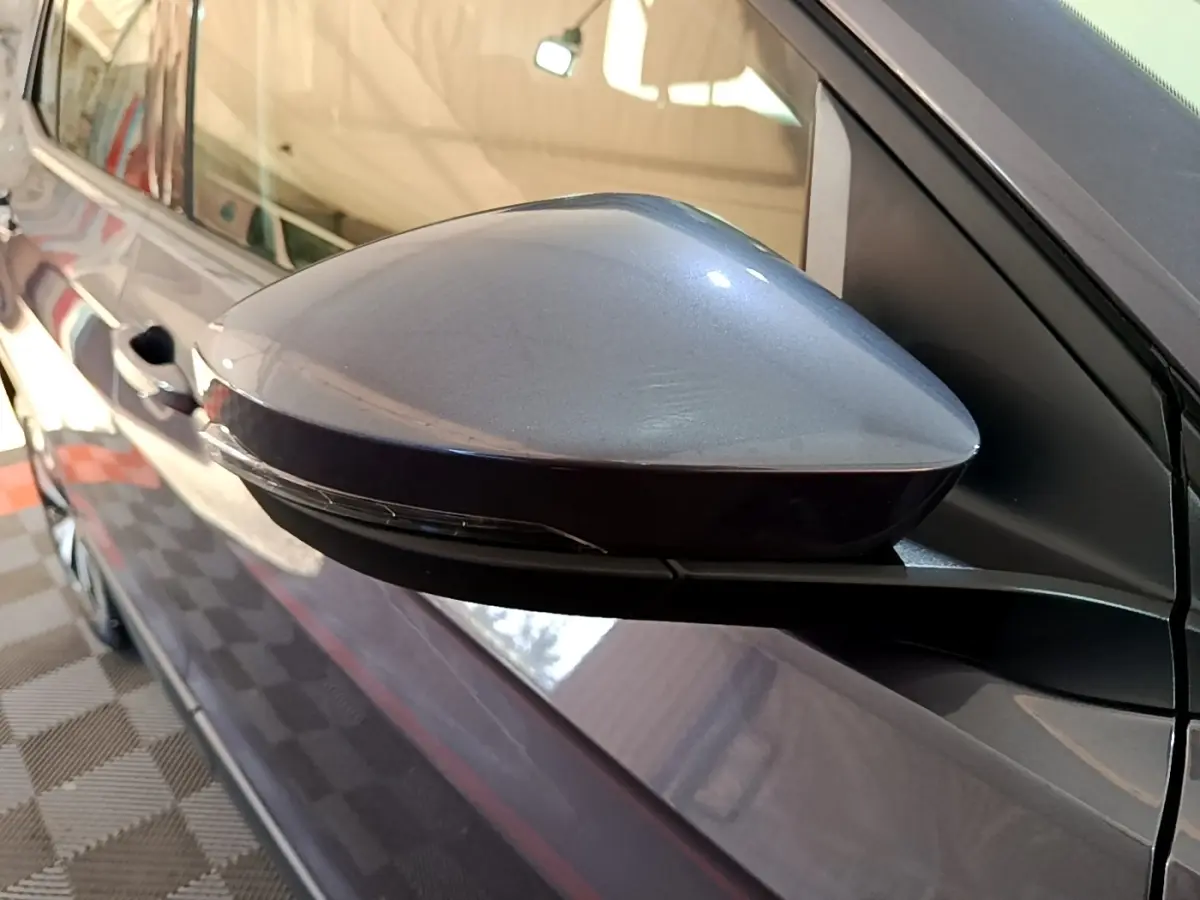 Rétroviseur côté gauche gris foncé du Volkswagen T-Cross 2023, avec poignée de porte visible en arrière-plan.