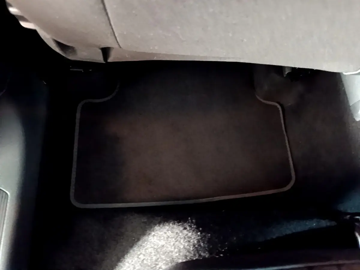 Vue du sol côté passager avant du Volkswagen T-Cross gris foncé, avec tapis de sol en tissu noir.