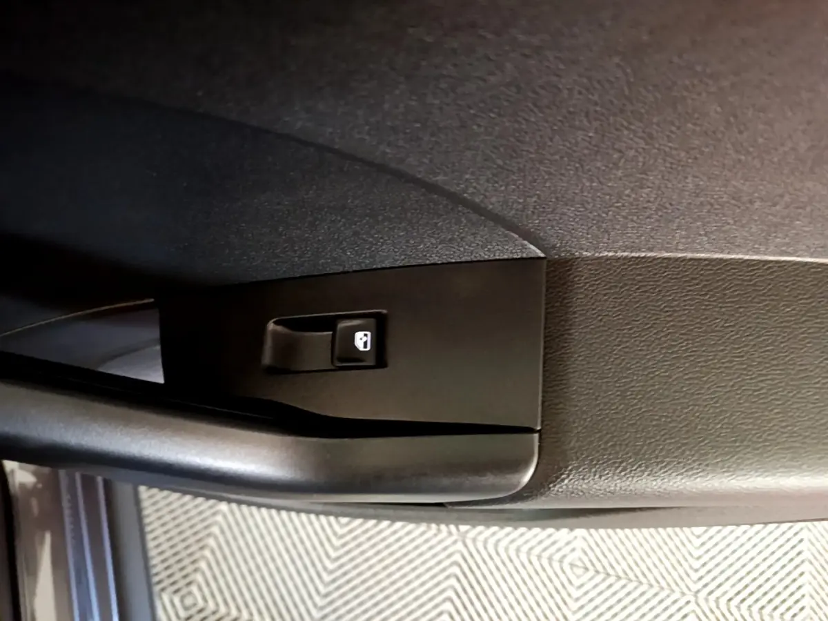 Détail de la poignée intérieure de porte côté gauche du Volkswagen T-Cross gris foncé, bouton de verrouillage visible.