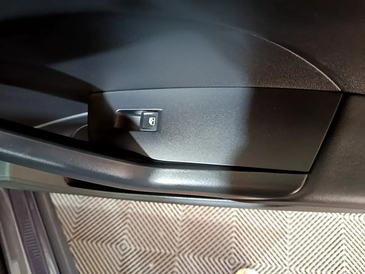 Détail du bouton de verrouillage des portes sur la portière intérieure côté conducteur du Volkswagen T-Cross gris foncé.