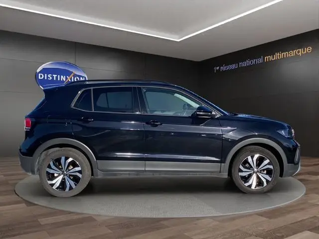 Vue latérale droite d'un Volkswagen T-Cross noir 2025 avec jantes alliage distinctives dans un showroom.