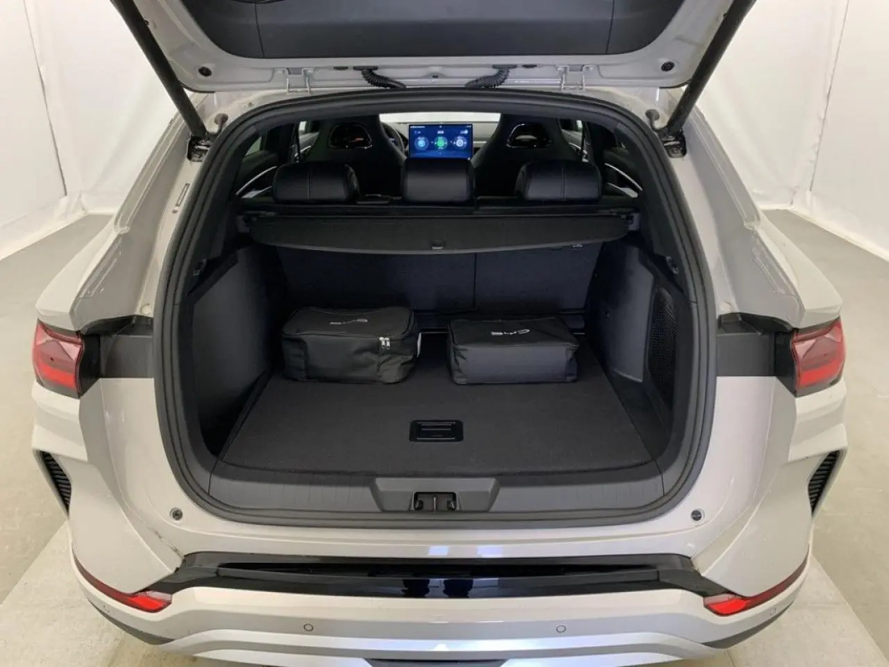 Vue arrière du coffre ouvert du BYD SEAL U 2025 en blanc Boundless Cloud, avec deux sacs noirs posés à l'intérieur.