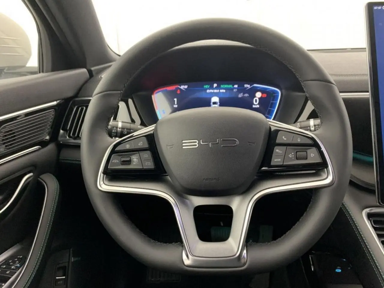 Vue rapprochée du volant noir en similicuir vegan du BYD SEAL U 2025 avec tableau de bord numérique lumineux.