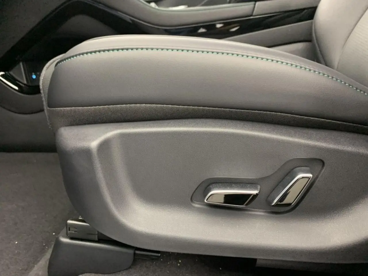 Gros plan sur les commandes de réglage électrique du siège conducteur en similicuir noir avec surpiqûres vertes du BYD SEAL U 2025.