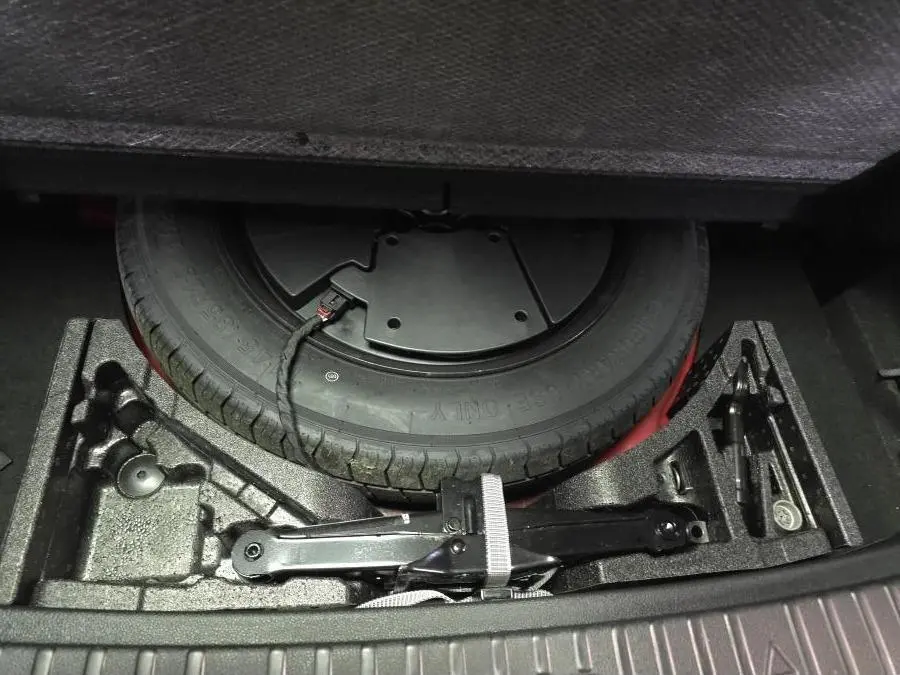 Vue rapprochée de la roue de secours et des outils de bord dans le coffre du Skoda Kodiaq rouge Sportline 2021.