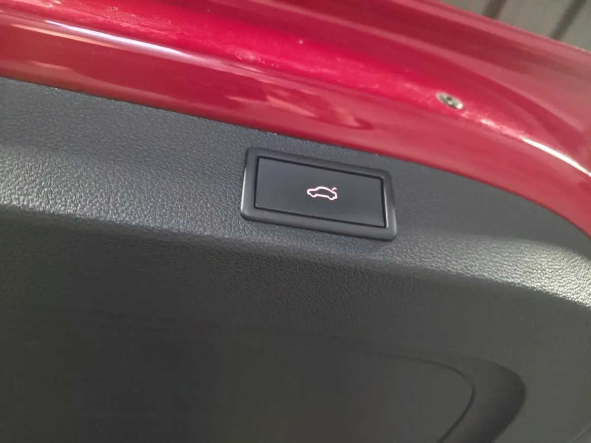 Bouton d'ouverture électrique du hayon sur la partie intérieure rouge du coffre d'un Skoda Kodiaq Sportline rouge.