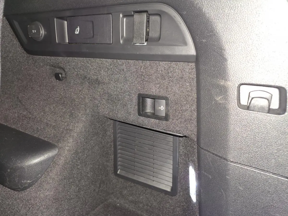 Détail intérieur du coffre du Skoda Kodiaq Sportline 2021, montrant les commandes de banquette rabattable et prise 12V.