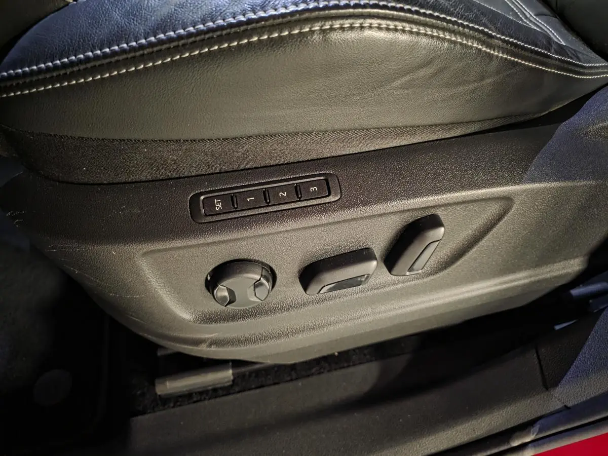 Gros plan sur les commandes de réglage électrique du siège conducteur en cuir noir du Skoda Kodiaq rouge.