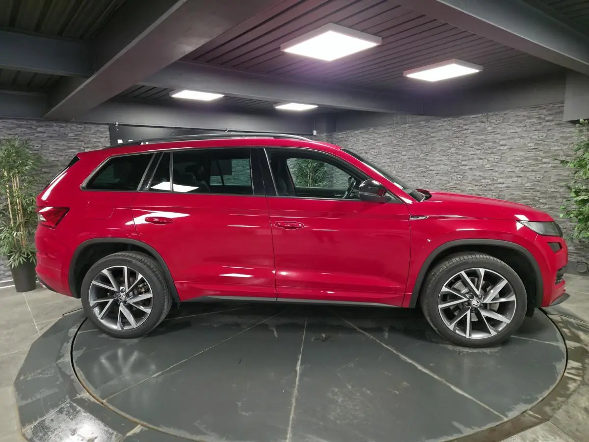 Vue latérale droite d'un SUV SKODA KODIAQ rouge 7 places avec jantes alliage 20 pouces dans un showroom.