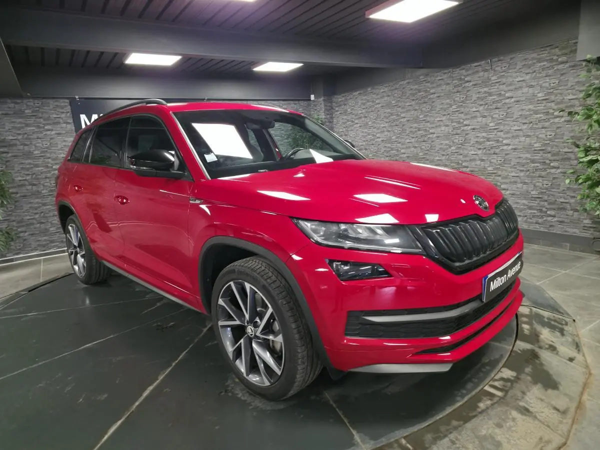 SKODA KODIAQ rouge en 3/4 avant droit, avec jantes alliage anthracite et calandre noire sportive.
