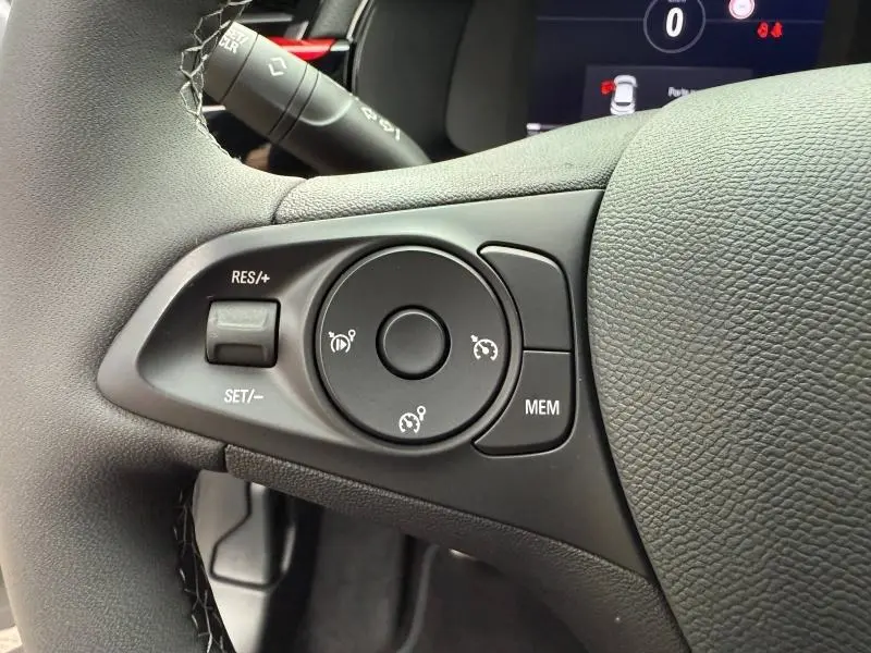 Gros plan sur les commandes noires du régulateur de vitesse au volant cuir noir de l'Opel Corsa 2023.