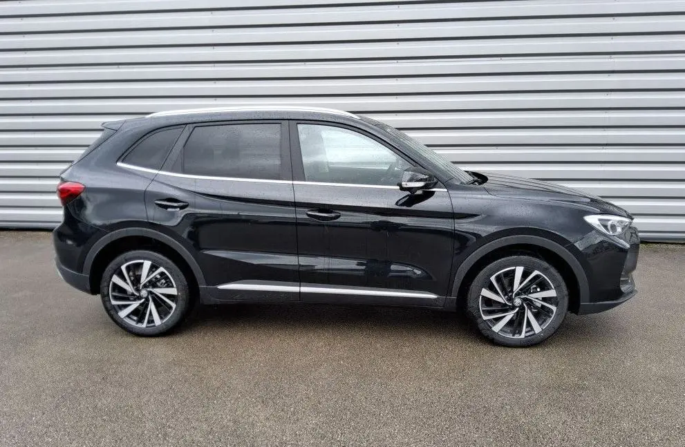 Vue de profil côté gauche du SUV MG ZS 1.5 Hybrid+ 197 Luxury en Pebble Black avec jantes alliage bicolores.