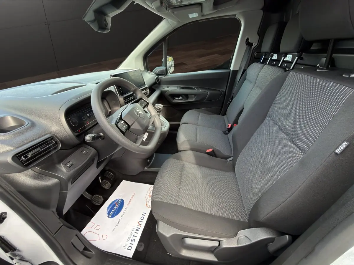 Intérieur avant du Citroën Berlingo blanc 2026, vue côté conducteur montrant les sièges 3 places et le tableau de bord moderne.
