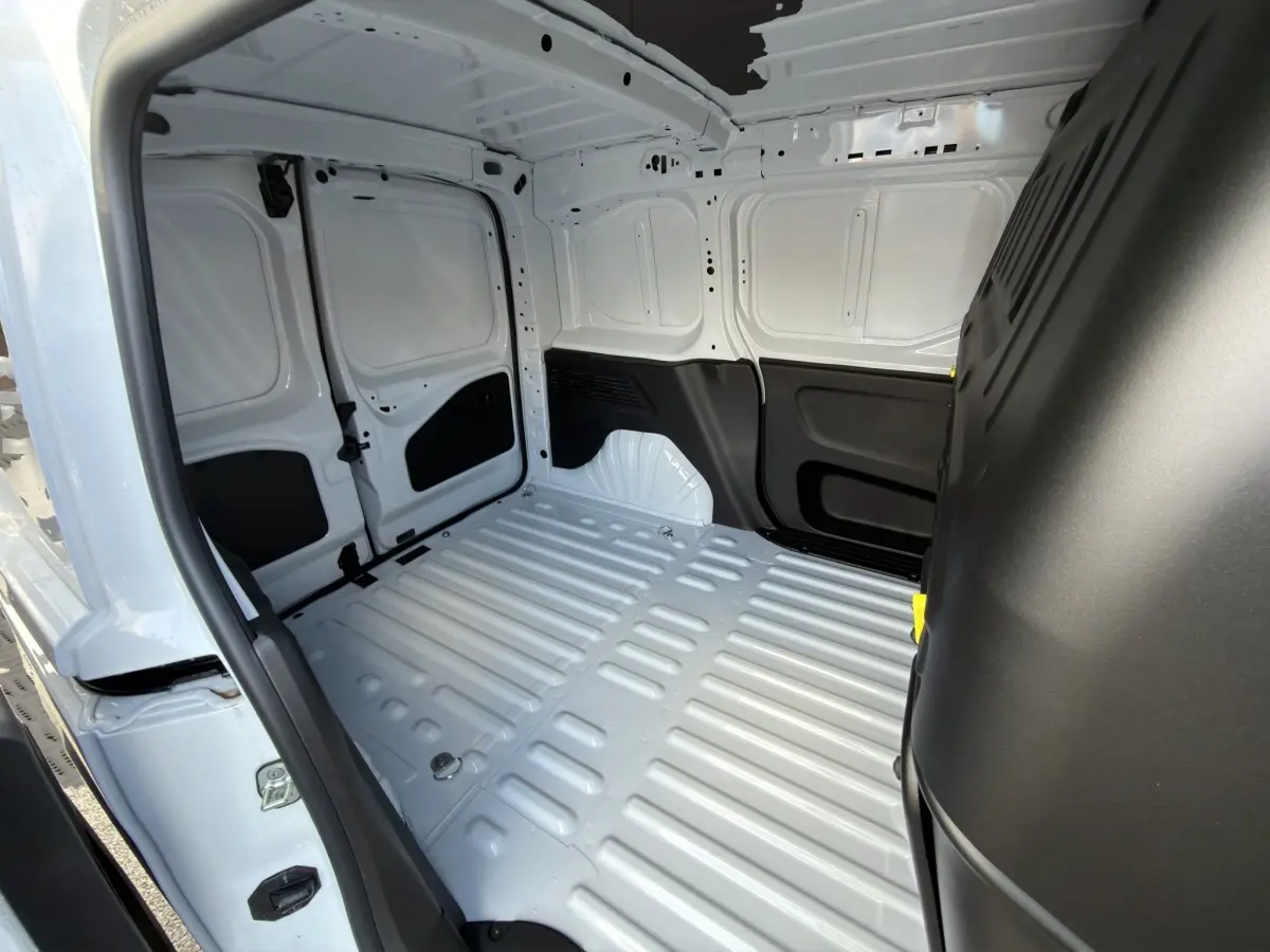 Vue intérieure arrière du Citroën Berlingo blanc 2026, montrant l’espace de chargement vide et les parois métalliques.