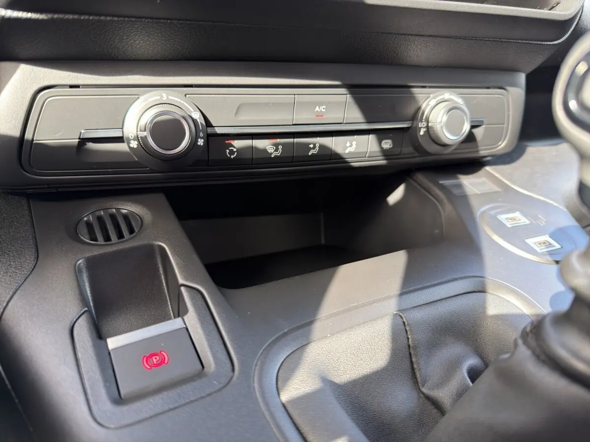Gros plan sur la console centrale noire du Citroën Berlingo 2026, montrant les commandes de climatisation et frein électrique.