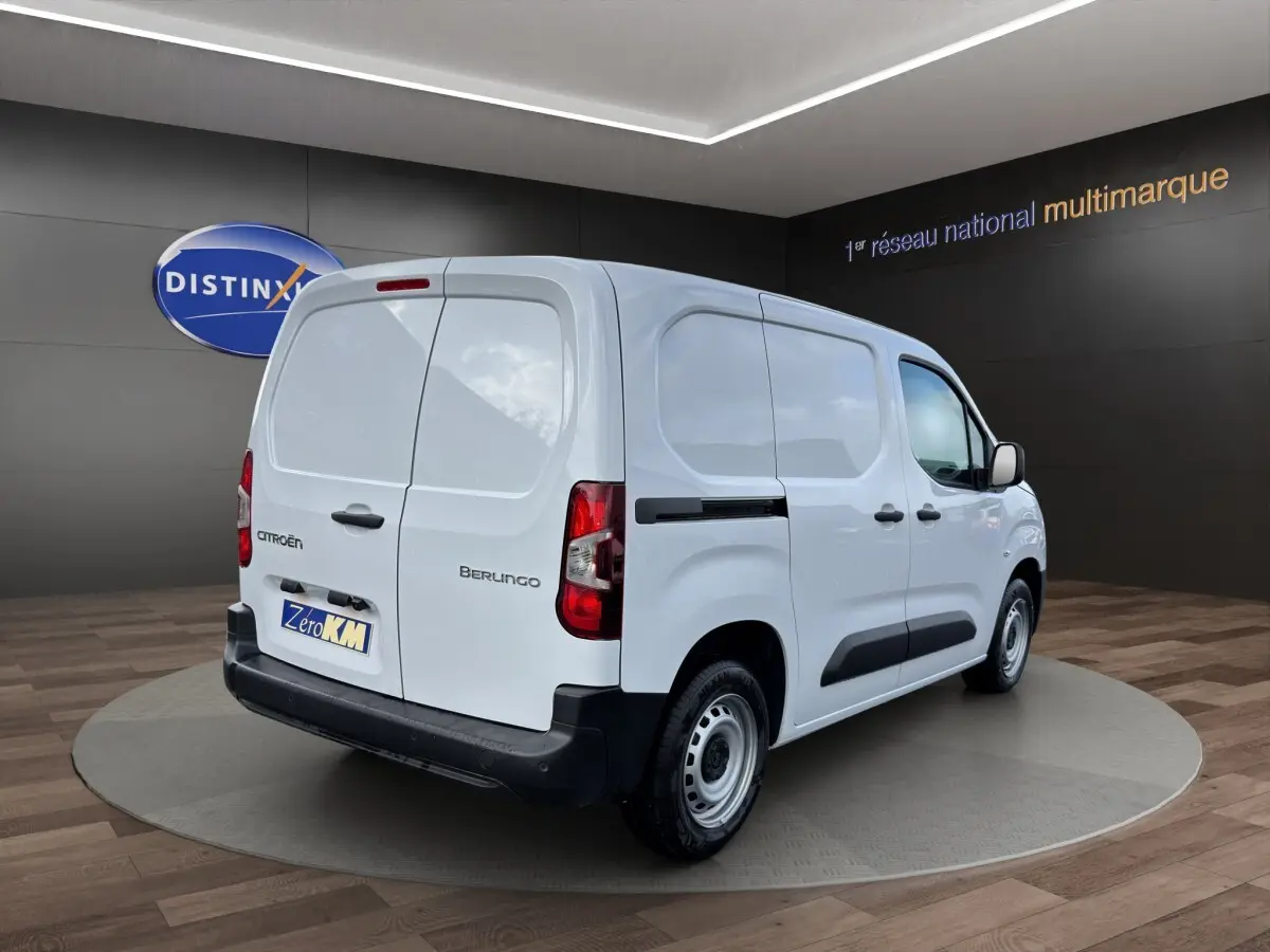 Vue 3/4 arrière droite d’un utilitaire Citroën Berlingo blanc avec portes arrière battantes et protections latérales noires.