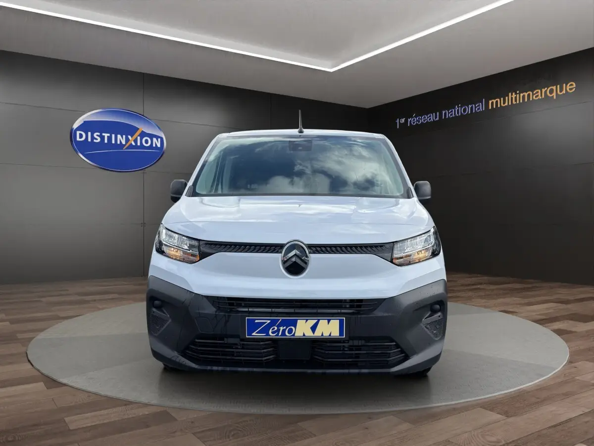 Vue avant d’un Citroën Berlingo blanc 2026 avec calandre noire et plaque Zéro KM en showroom.