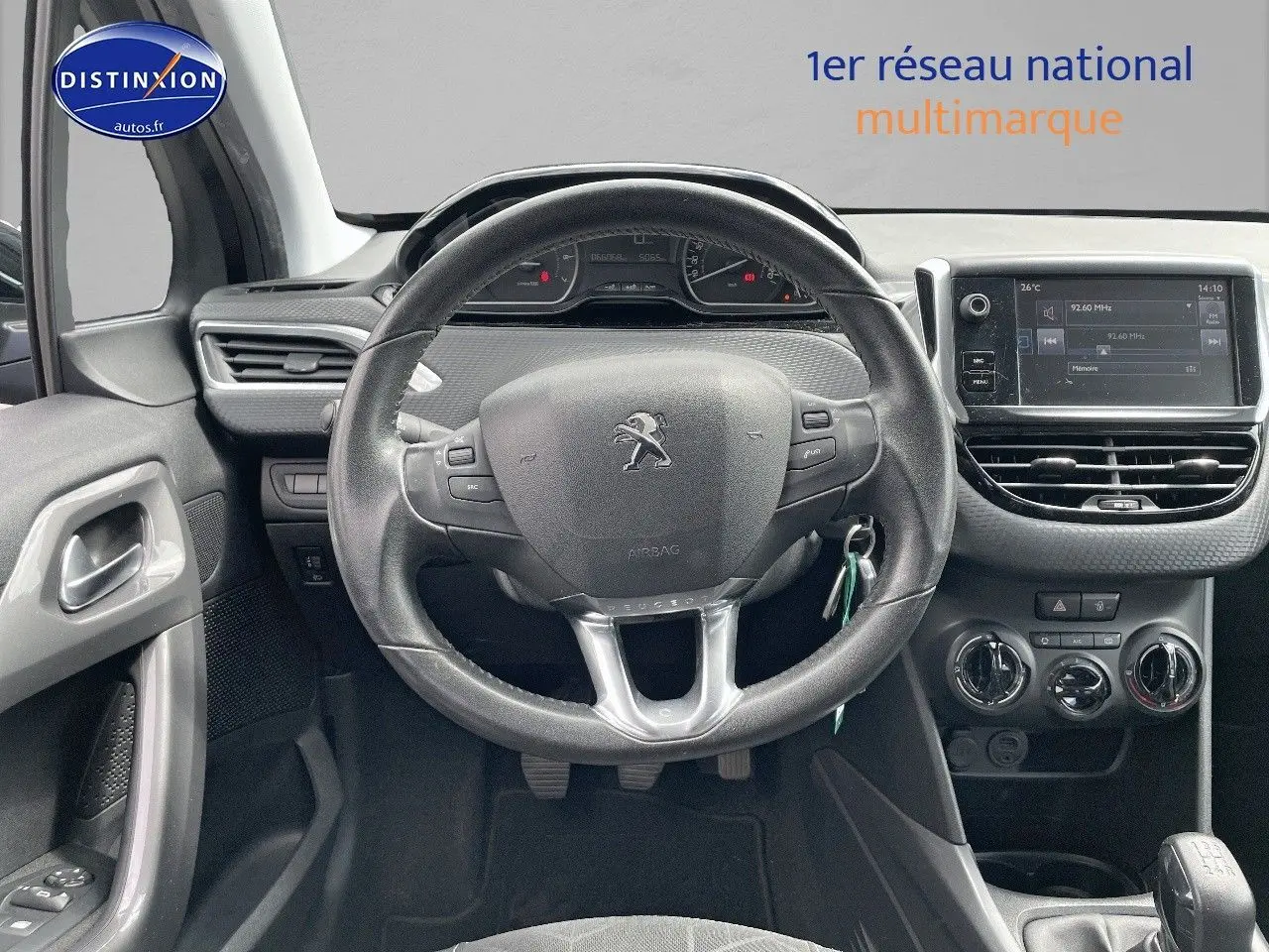 Vue intérieure centrée sur le volant Peugeot 2008 noir métal, tableau de bord et console avec écran tactile et commandes climatiques.