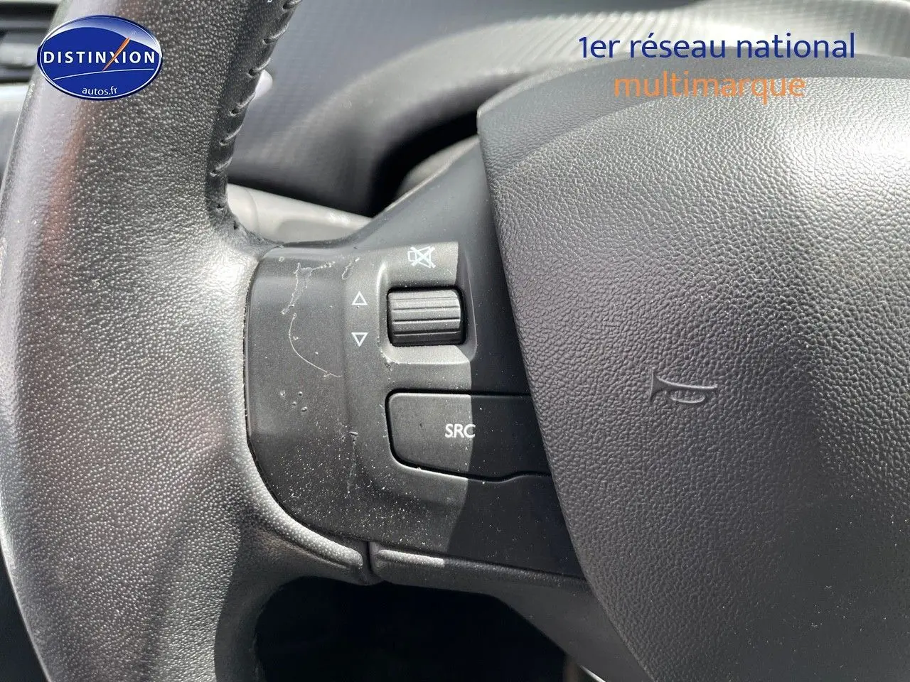 Gros plan sur la partie gauche du volant noir du Peugeot 2008 2016, avec commandes audio intégrées.