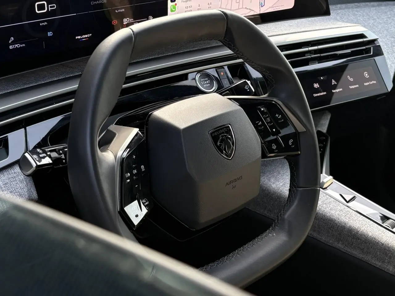 Vue rapprochée du volant cuir noir et du tableau de bord numérique du Peugeot 3008 Hybrid blanc Okenite 2025.