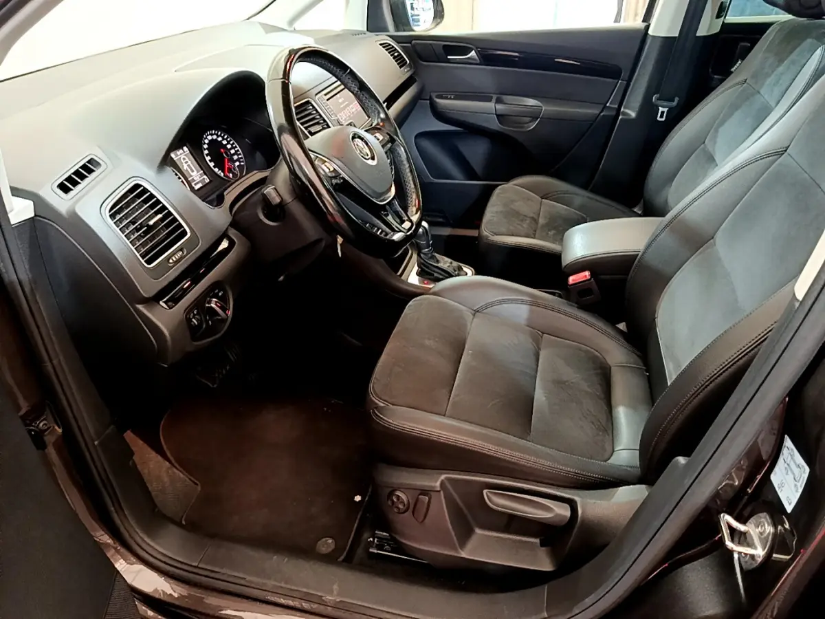 Vue intérieure côté conducteur de la Volkswagen Sharan marron, avec sièges en cuir et tableau de bord noir.