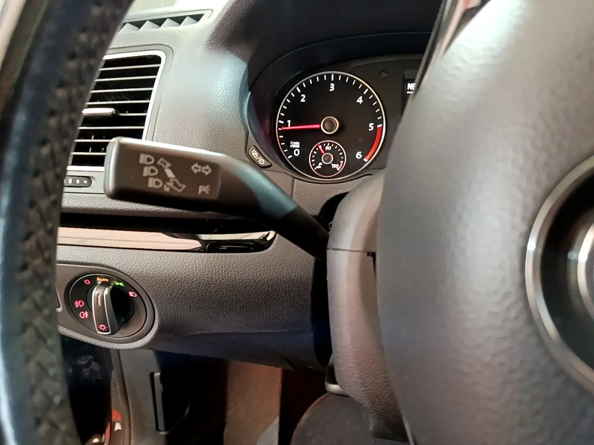 Gros plan intérieur sur le volant et le commodo de clignotant du Volkswagen Sharan 2.0 TDI marron, tableau de bord visible.