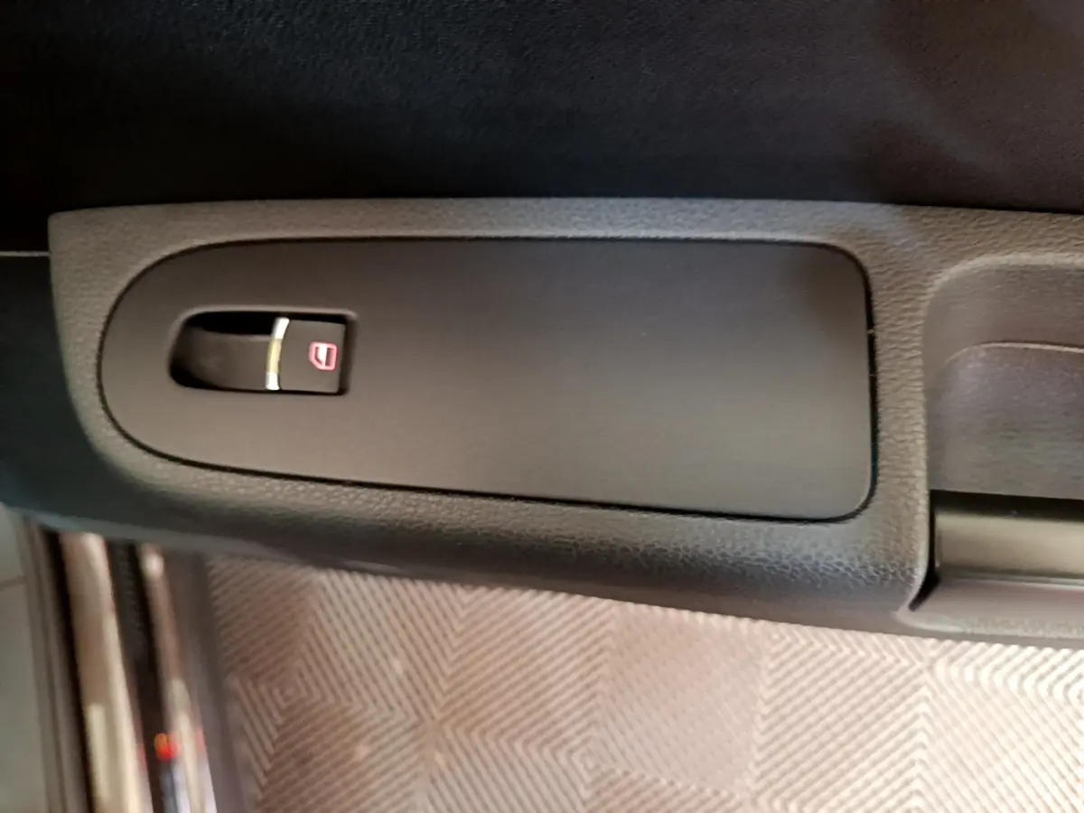 Gros plan sur la commande de verrouillage centralisé noire dans l’habitacle du Volkswagen Sharan marron.