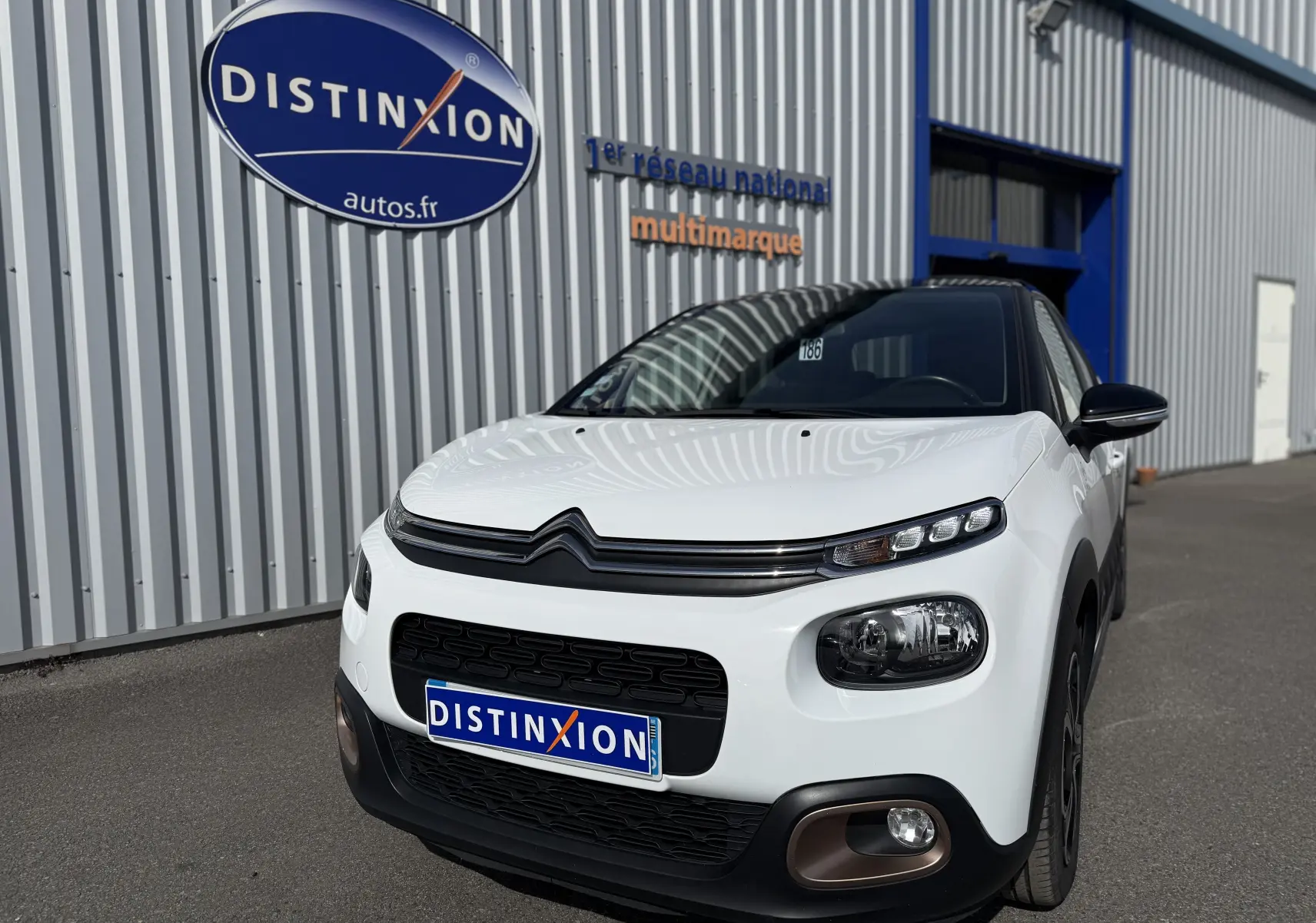 Citroën C3 1.2 PureTech 83 Origins blanc toit noir vue 3/4 avant avec calandre et phares distinctifs.