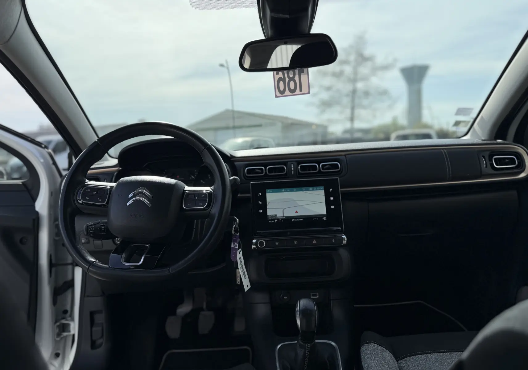 Vue intérieure avant de la Citroën C3 1.2 PureTech 83 Origins 2019, tableau de bord noir avec écran tactile et volant multifonctions.