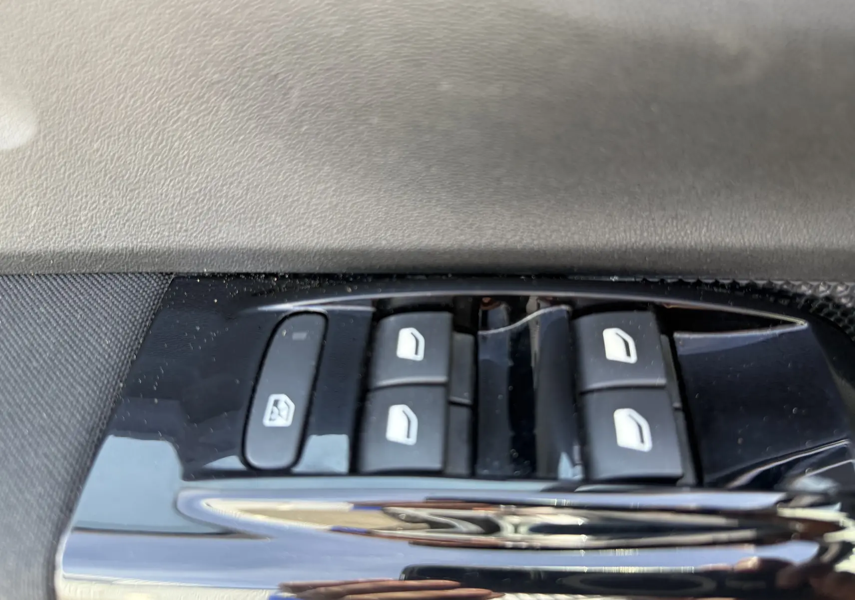 Gros plan sur les commandes des vitres électriques côté conducteur d'une Citroën C3 blanche toit noir, version 2019.