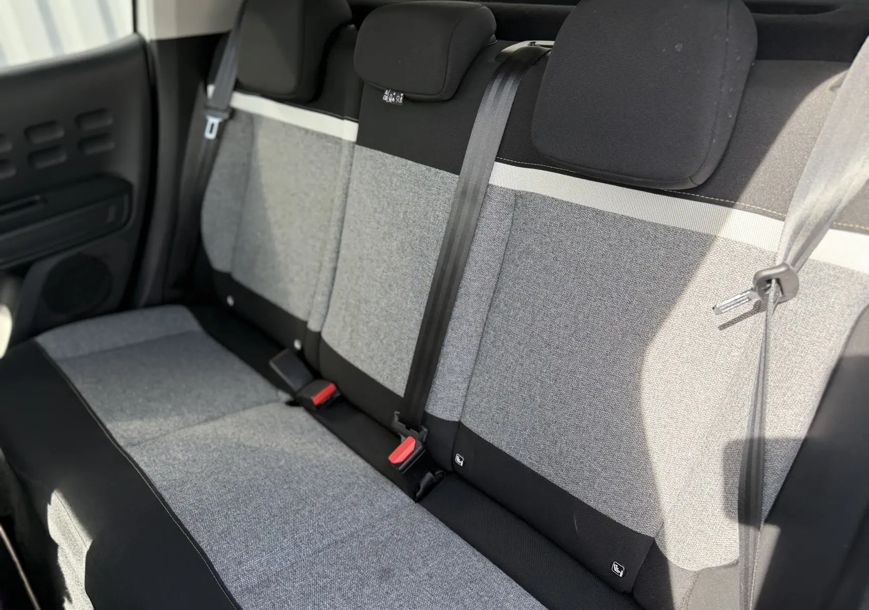 Vue intérieure de la banquette arrière en tissu gris et noir de la Citroën C3 2019, avec ceintures de sécurité visibles.