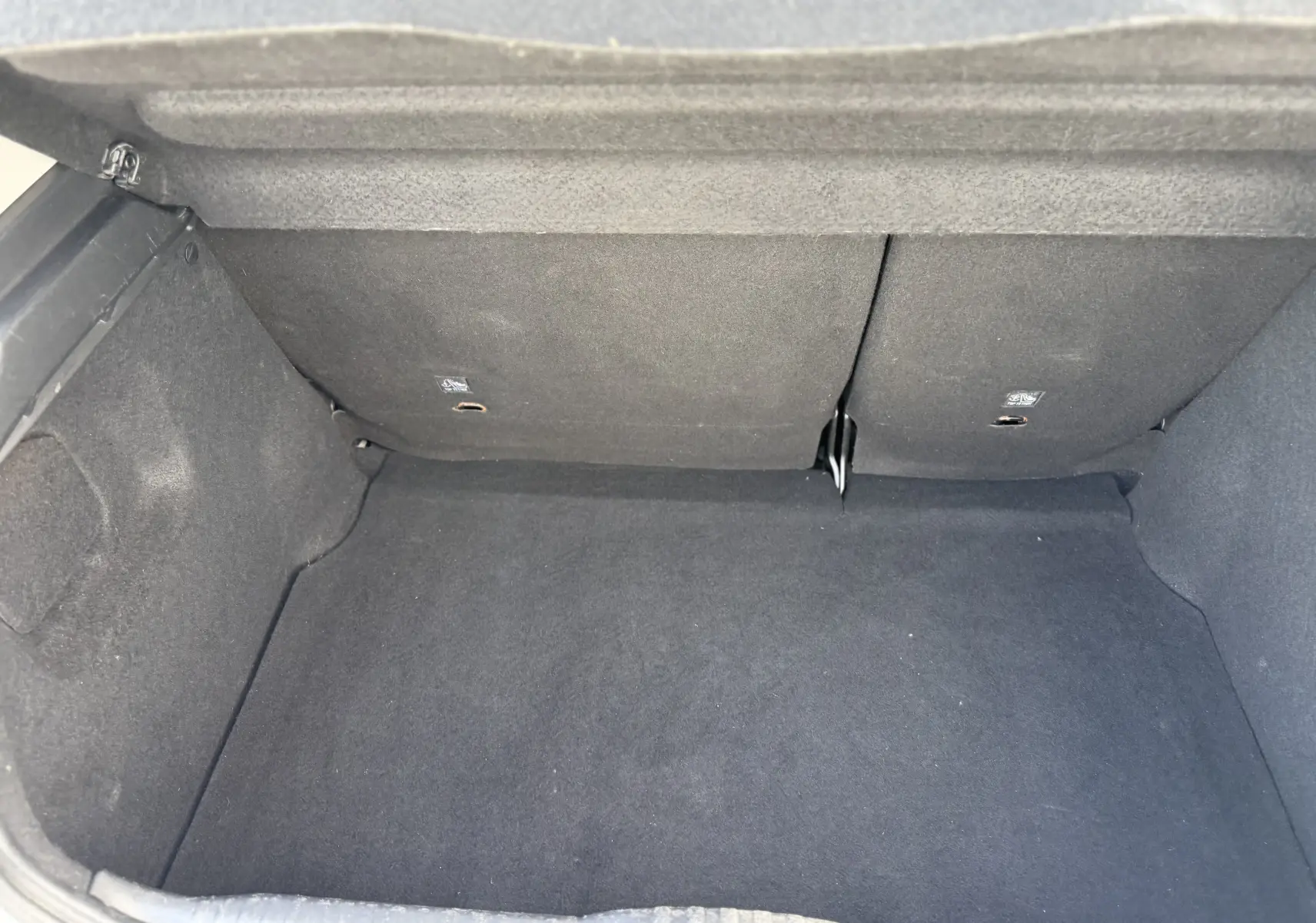 Vue intérieure du coffre vide de la Citroën C3 1.2 PureTech 83 Origins, avec revêtement noir uniforme.