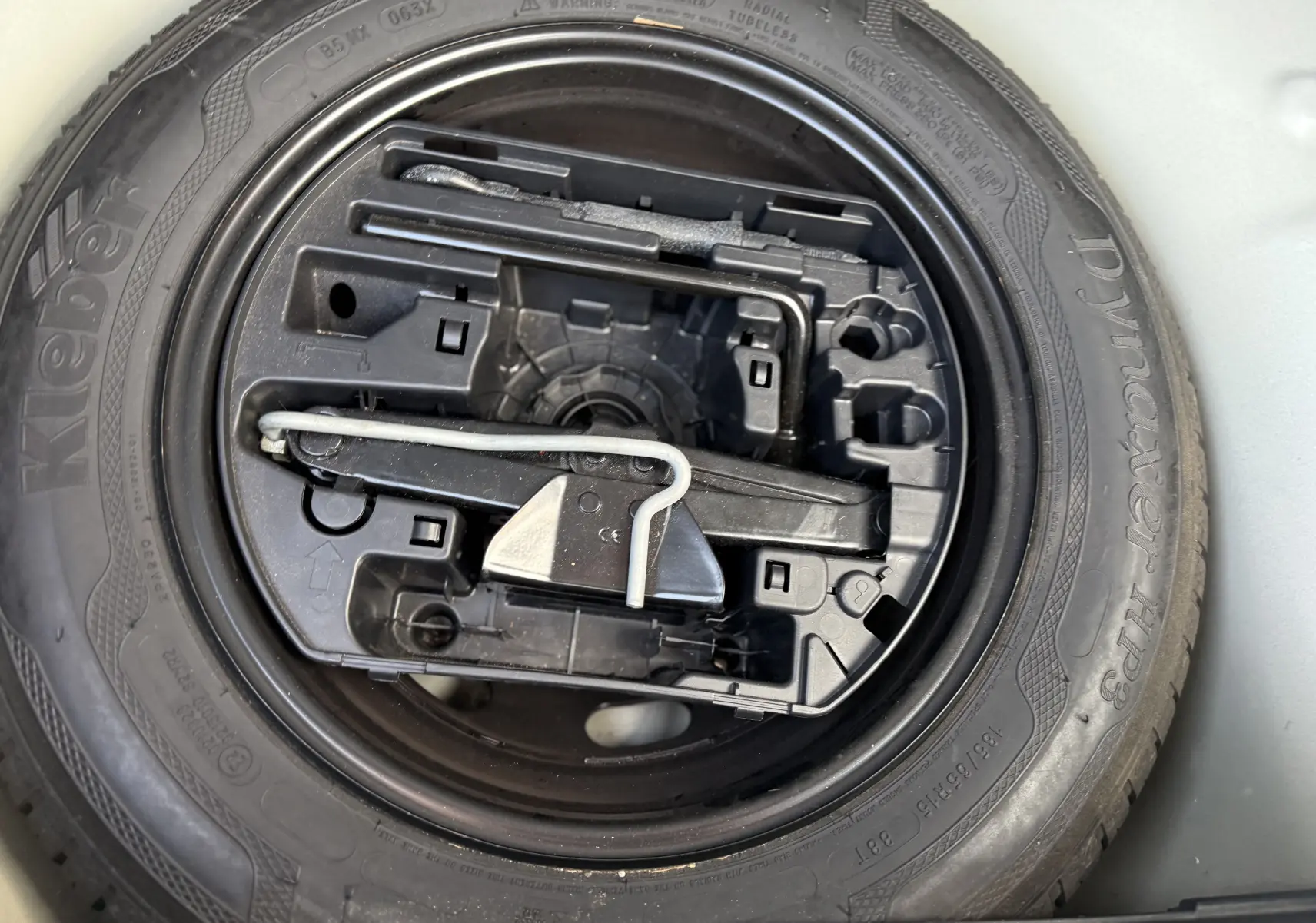 Gros plan sur la roue de secours et le kit d'outils dans le coffre d'une Citroën C3 blanc toit noir 2019.