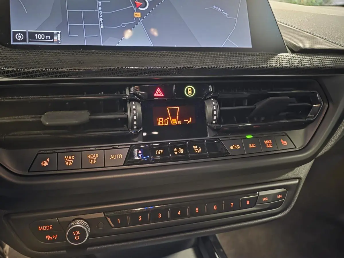 Détail de la console centrale de la BMW Série 1 116d M Sport 2024 avec commandes climatisation et écran tactile.