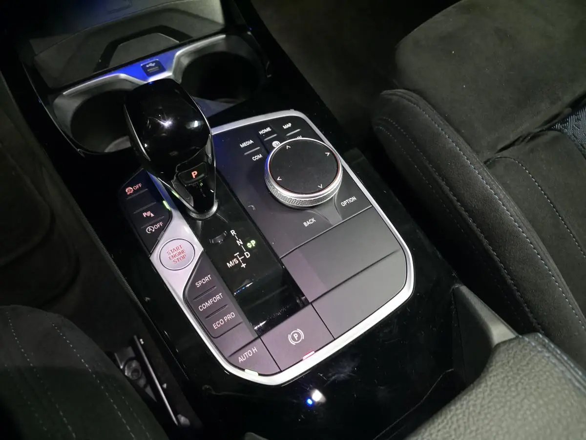 Gros plan sur la console centrale noire avec sélecteur de boîte automatique et molette iDrive de la BMW Série 1 rouge.