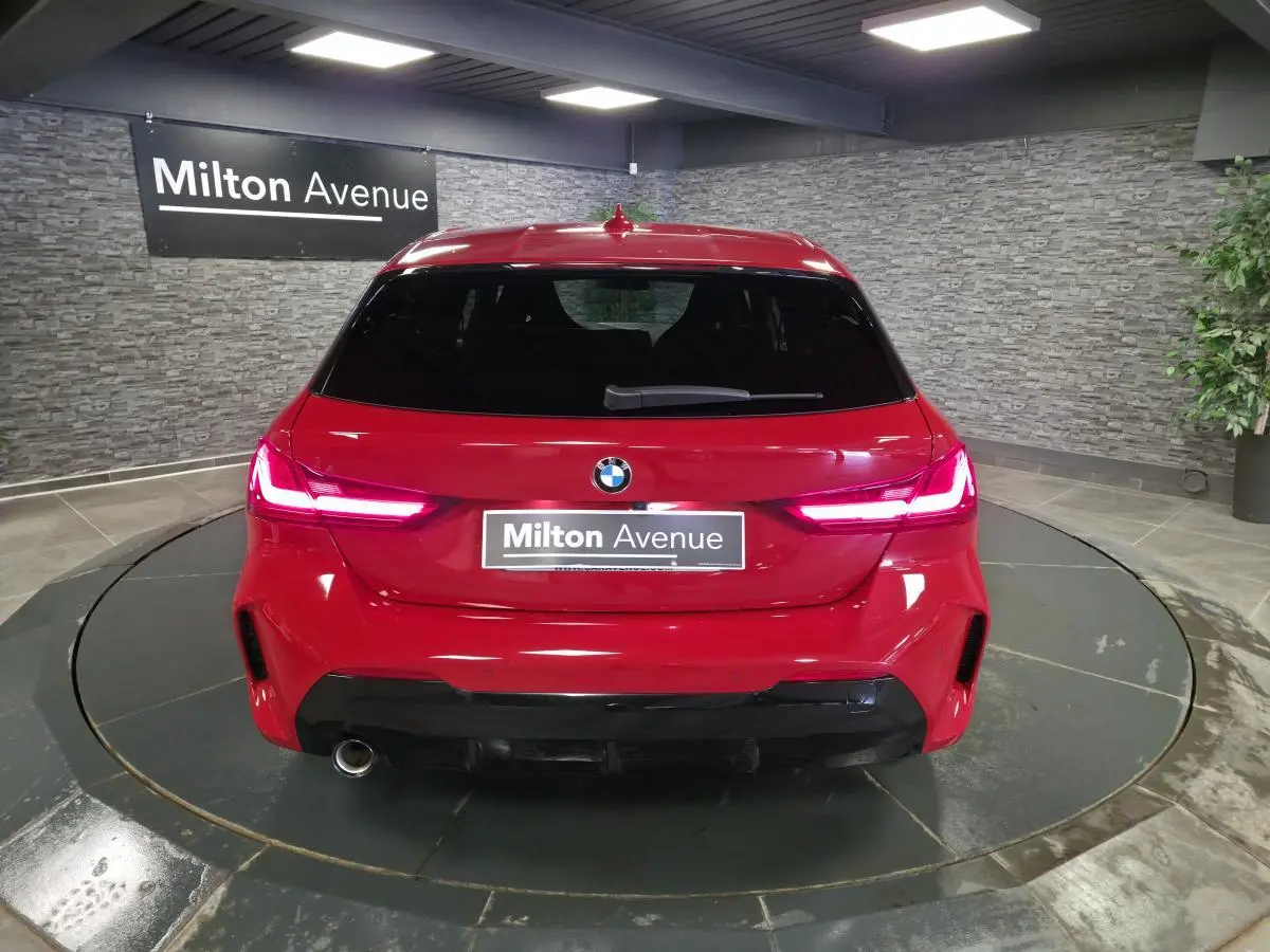 Vue arrière d'une BMW Série 1 116d M Sport rouge métallisé avec feux LED et sortie d'échappement chromée.