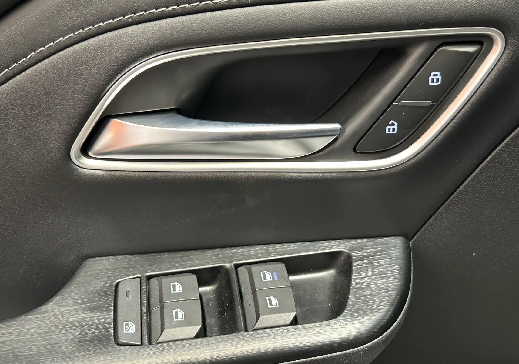 Poignée de porte intérieure côté gauche en cuir noir avec commandes de verrouillage et lève-vitres du MG ZS 1.5 Hybrid+ Dover White.