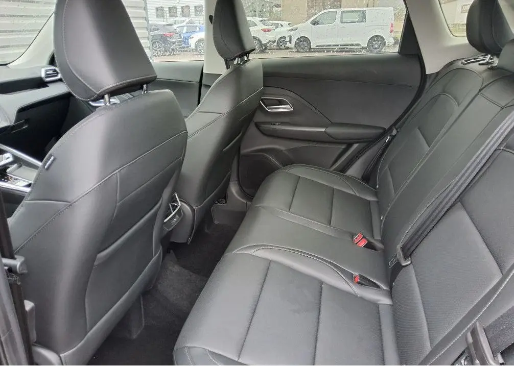Vue intérieure arrière côté droit du MG ZS 1.5 Hybrid+ 197 Luxury avec sièges cuir noirs et ceintures de sécurité visibles.